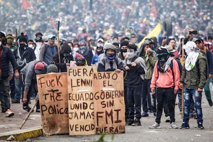 Manifestantes enmascarados sostienen carteles contra el presidente Lenin Moreno