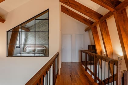 Subiendo la escalera de cedro, un cuarto de huéspedes mínimo se amplía gracias a la ventana que da al ambiente principal en doble altura.