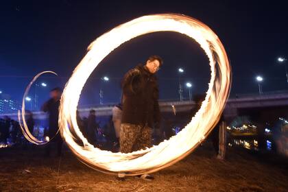 Los surcoreanos giran latas de carbón quemado durante un evento para celebrar la próxima luna llena del año nuevo lunar en un parque a orillas del río en Seúl, lo hacen para fertilizar el suelo y eliminar las plagas no deseadas, lo que garantiza una cosecha próspera