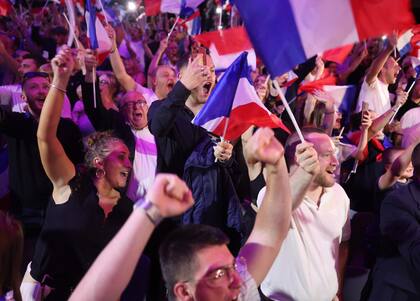 Sus partidarios reaccionan cuando  Marine Le Pen pronuncia un discurso durante la velada de resultados de la primera vuelta de las elecciones parlamentarias en Henin-Beaumont, al norte de Francia, el 30 de junio de 2024.