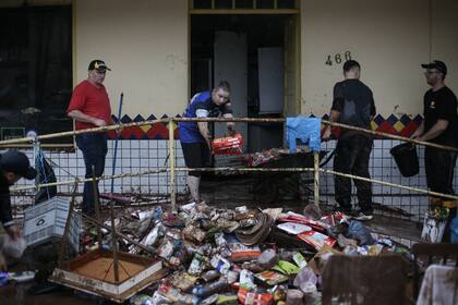 Los trabajadores del supermercado Swarowsky limpian y retiran productos de la tienda afectada por las fuertes lluvias en Sinimbu, en la región de Vale do Rio Pardo de Rio Grande do Sul, Brasil, el 1 de mayo de 2024