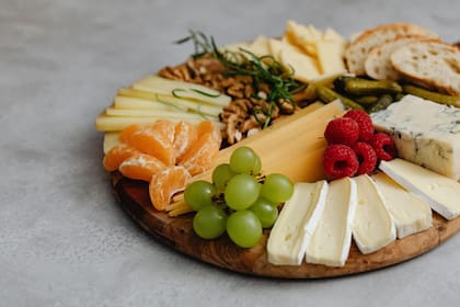 Tabla de quesos clásica con fruta fresca, frutos secos, pan y encurtidos