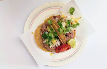 Tacos de cerdo y piña en tortilla de maíz, con cebolla, cilantro, ananá y jalapeños.