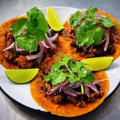 Tacos de entraña marinada, chuleta ahumada, frijoles, salsa macha, chicharrón, cebolla morada, cilantro, lima