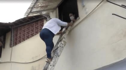 Tâmara Bahia, la hija de Eneide Bahia de Souza, baja de su casa a la calle con la ayuda de una escalera plegable para poder ir a trabajar