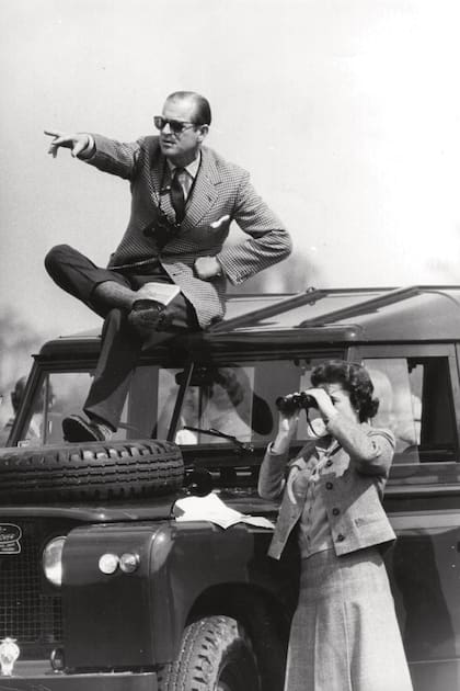 También los une el amor por los caballos. Felipe, sentado en el techo de un Land Rover, le señala a la Reina los competidores durante un campeonato de salto en Badminton, el 20 de abril de 1968.