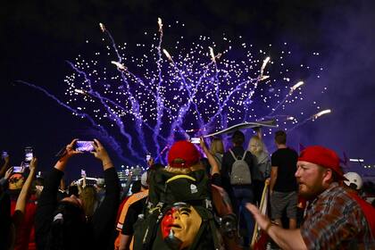 Los espectadores toman videos desde teléfonos celulares durante una exhibición de fuegos artificiales en preparación para el Super Bowl LV en Tampa, Florida.