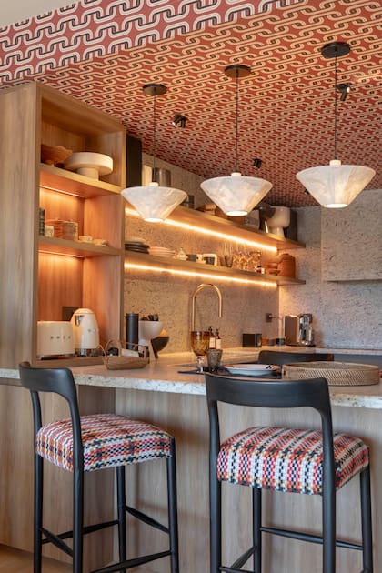 Tanto en la cocina como en el hall de entrada, el mismo empapelado de Tienda Wallpaper reaparece como hilo conductor.