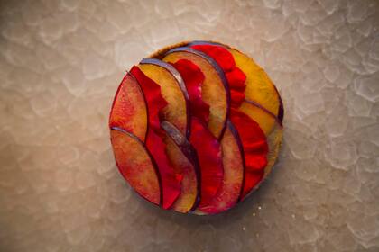 Tarta de chocolate y almendras con ganache de chocolate blanco, ciruelas
y pétalos de rosa.