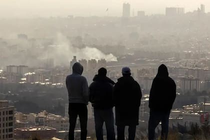 Iraníes observan Teherán desde una colina durante los ataques.