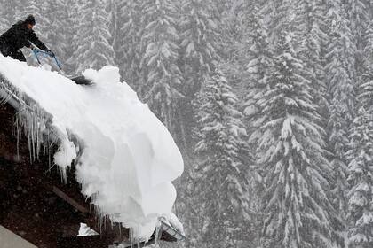 Trabajadores de un hotel en Filzmoos, Austria, remueven la nieve de los techos, tras la intensa caída hay temor de que colapsen los techos