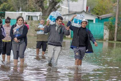 Los voluntarios caminan por las calles inundadas repartiendo agua.