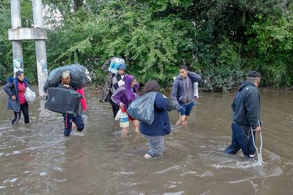 Con algunas pocas pertenencias que pudieron salvar de la inundación, varios vecinos se dirigen a lugares más altos.