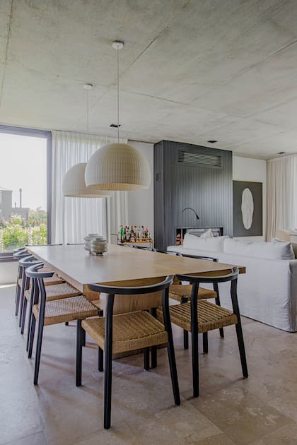 TEn el comedor, mesa enchapada en roble americano (diseño de MMS ejecutado por Inercia) y sillas ‘Asta’ (Marini). Lámparas colgantes (Iluminación Agüero). Carrito-bar (Bull). Toda la planta baja tiene piso de Travertino.