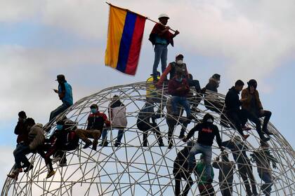 Manifestantes sobre la escultura “Esfera de Movimientos Oscilantes” en Quito