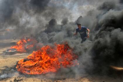 Un palestino camina a través del humo de los neumáticos quemados durante las protestas