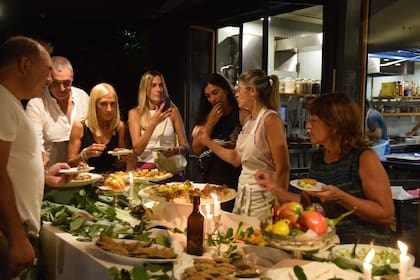Tere recibe a los asistentes, presenta al cocinero invitado, ayuda en la cocina y guía a los participantes durante todo el proceso.