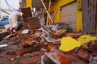 Un residente recupera sus pertenencias entre los escombros de una casa derrumbada después de un terremoto que sacudió Machala,