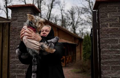 Tetiana Ustymenko, residente de Bucha, juega con su perro fuera de su casa, donde su hijo está enterrado en el jardín, en Bucha, al noroeste de Kiev, el 6 de abril de 2022, durante la invasión de Rusia a Ucrania