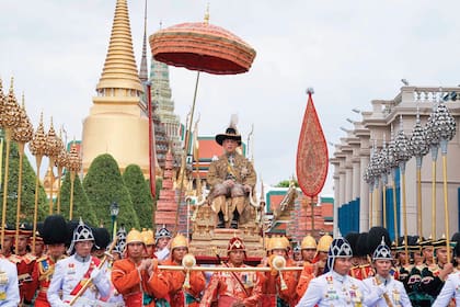 Una pintoresca imagen de Rama X, vestido con tradicional traje dorado y sombrero de ala ancha, sobre el palanquín o silla real sobre la que recorrió las calles.