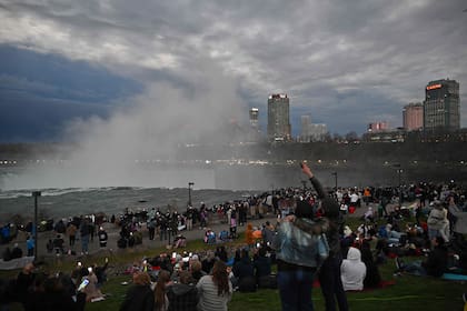 The sky darkens as people look up at the sun during the total solar eclipse across North America, at Niagara Falls State Park in Niagara Falls, New York, on April 8, 2024. This year's path of totality is 115 miles (185 kilometers) wide and home to nearly 32 million Americans, with an additional 150 million living less than 200 miles from the strip. The next total solar eclipse that can be seen from a large part of North America won't come around until 2044. (Photo by ANGELA WEISS / AFP)�
