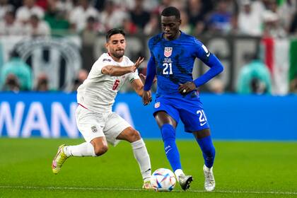 Tim Weah lleva la pelota ante la marca de Milad Mohammadi en el comienzo de Irán - Estados Unidos, en Qatar 2022.