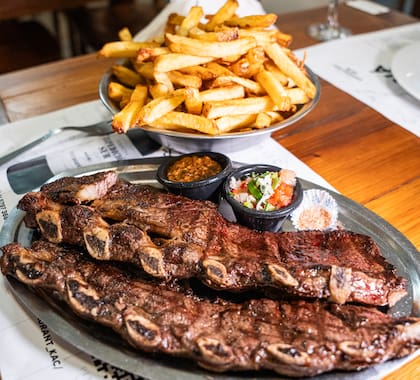 Tira de asado con papas fritas, uno de los platos que salen de la parrilla