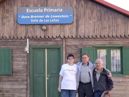 Tito Lowenstein junto a Elsa Karam, histórica empleada del valle, y Luis "Yiyo" Ballarini, director del Museo Las Leñas, frente a la escuela primaria que lleva el nombre de su madrina, Dora Brenner de Lowenstein, madre de Tito.