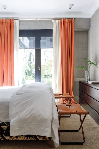 Todo listo par un buen descanso en el cuarto de la diseñadora Martina Correa. Paredes enteladas en rafia, cortinas dobles, con las principales en terciopelo color durazno y roller screen negras (todo de Caro Deane).