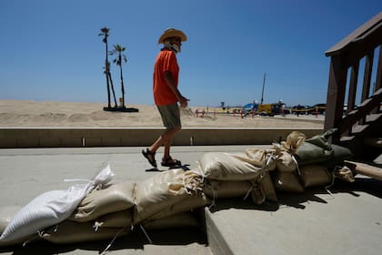 Tom Ostrom, residente en Seal Beach, pasa junto a una vivienda protegida con bolsas de arena, en Seal Beach, California, el 18 de agosto de 2023. (AP Foto/Damian Dovarganes)