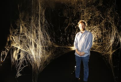 Tomás Saraceno junto a la tela construida por miles de arañas en el Mamba