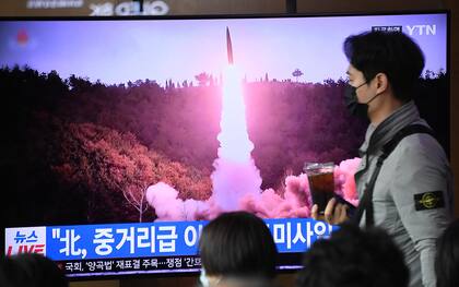 TOPSHOT - A man walks past a television screen showing a news broadcast with file footage of a North Korean missile test, at a railway station in Seoul on April 13, 2023. - North Korea fired a ballistic missile on April 13, Seoul's military said, prompting Japan to briefly issue a seek shelter warning to residents of the northern Hokkaido region. (Photo by Jung Yeon-je / AFP)