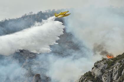 TOPSHOT - An Air Tractor AT-802A firefighting plane drops water during fire containment operations near Artesa de Segre, in Catalonia on June 16, 2022. - Emergency services battled several wildfires as Spain remained in the grip of an exceptional heatwave that has seen temperatures reach 43 degrees Celsius (109 degrees Farenheit). The most alarming blaze, near Baldomar in Catalonia, has already destroyed 500 hectares of forest but could spread to over 20,000, the government in the northwestern region said. (Photo by Pau BARRENA / AFP)