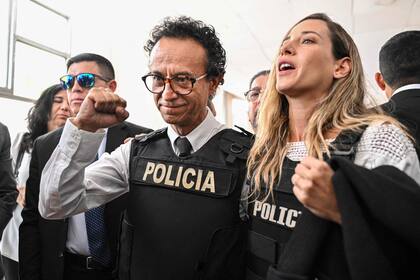 TOPSHOT - El periodista y candidato presidencial por el partido Construye, Christian Zurita (C), gesticula junto a su compañera de fórmula, la candidata a la vicepresidencia Andrea González (D), en Quito el 13 de agosto de 2023. (Foto de MARTIN BERNETTI / AFP)