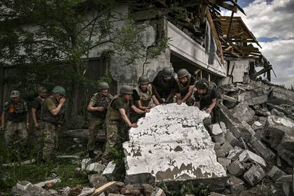 TOPSHOT -  Soldados ucranianos inspeccionan los restos de un depósito en Lysychansk. (Foto Archivo ARIS MESSINIS / AFP)