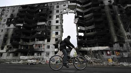 TOPSHOT - Un ciclista recorre la ciudad de Borodianka frente a un edificio destruido por la guerra. (Photo by Genya SAVILOV / AFP)
