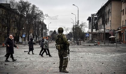 TOPSHOT - Un soldado ruso observa el paso de ciudadanos ucranianos en Mariupol (Photo by Alexander NEMENOV / AFP)