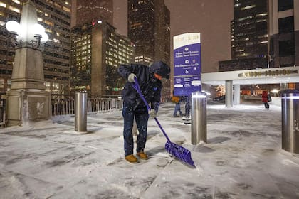 Un hombre palea la vereda durante una tormenta de invierno antes de las vacaciones de Navidad fuera de la Union Station, en Chicago el 22 de diciembre de 2022.