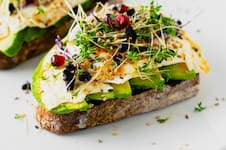 Tostadas con palta, láminas de queso y brotes