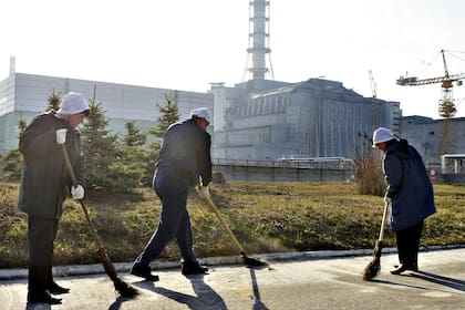 Trabajadores barren el polvo radiactivo frente al "sarcófago" que cubre el cuarto reactor dañado de la central nuclear de Chernobyl, en abril de 2006. El personal en el lugar solo trabaja unos minutos debido a los altos niveles de radiación que aún emana del reactor