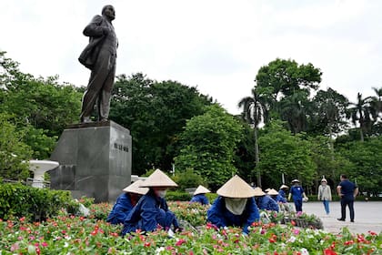 Trabajadores colocan macetas frente a un monumento del líder soviético Vladimir Lenin en Hanoi, a la espera de la llegada de Putin (Photo by Nhac NGUYEN / AFP)