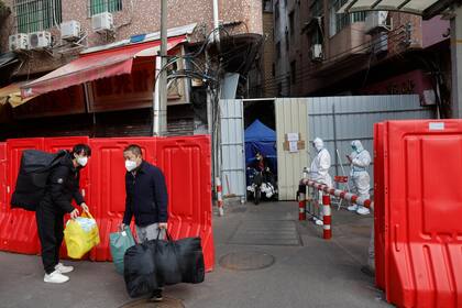 Trabajadores con sus pertenencias abandonan un pueblo con barricadas tras la relajación de las autoridades de las restricciones del COVID-19 en el distrito de Haizhu en Guangzhou, en la provincia de Guangdong, en el sur de China, el viernes 2 de diciembre de 2022.