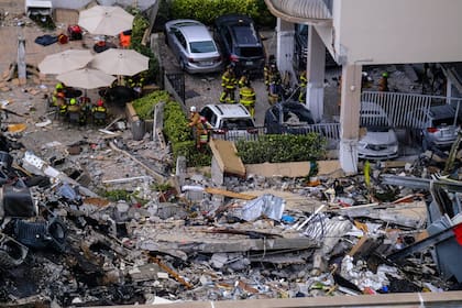 Trabajadores de emergencias inspeccionan los restos del estacionamiento y la pileta del edificio colapsado