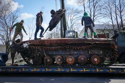 Trabajadores de la carretera cargan un tanque ruso destruido en una plataforma en el pueblo de Andriyivka, cerca de Kyiv, Ucrania, el lunes 11 de abril de 2022.