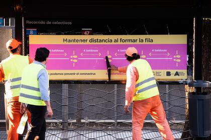 Trabajadores de la Ciudad aplican nuevos carteles en una estación de Metrobus