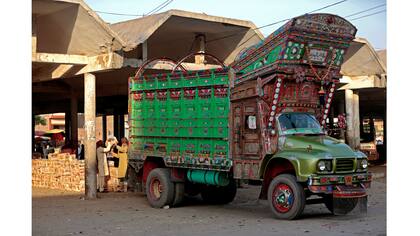 Trabajadores descargan fruta de un camión decorado en el mercado mayorista de Faisalabad