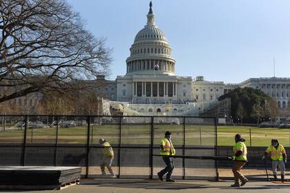 Trabajadores instalan vallas frente al Capitolio luego de los desmanes de ayer