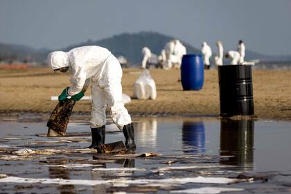 Trabajadores limpian petróleo en una playa tailandesa tras un derrame causado por una fuga en un oleoducto submarino