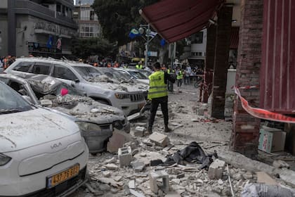 Trabajadores municipales limpian la calle de un edificio alcanzado por un ataque con proyectiles iraníes en Ramat Gan, en el centro de Israel