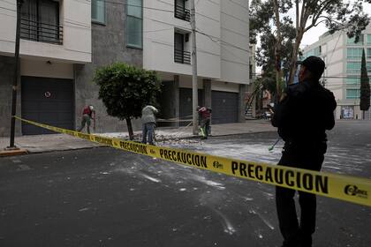 Trabajadores remueven escombros que cayeron del frente de un edificio durante el sismo, en la ciudad de México